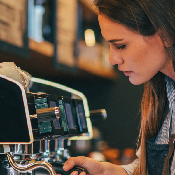 A barista in coffee shop handing the espresso machine  carefully